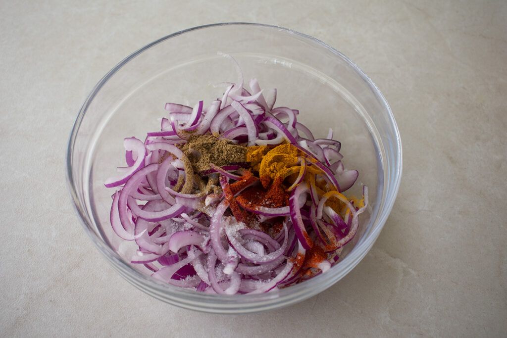 Cebolla cortada en juliana con especias para preparar Bhajis de cebolla