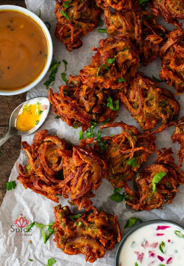 Crujientes Bhajis de cebolla servido con salsa de yogur y chutney de mango